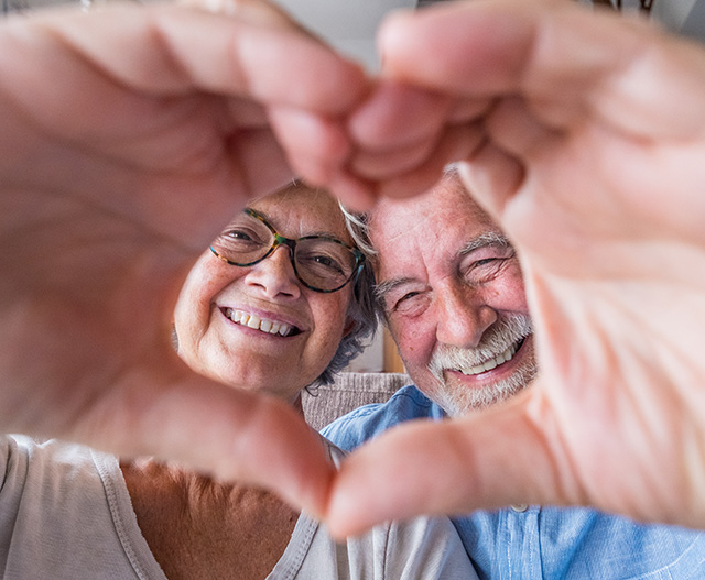 Older couple making heart with hands, selfie